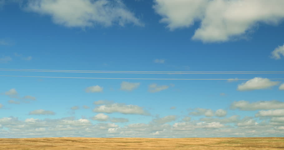 Driving plate side view on a highway through open plains and farmland in Midwestern United States agricultural fields under a wide sky rural travel and American heartland concept
