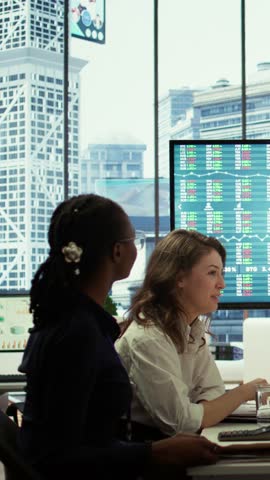 Vertical Video Business associates collaborating at the conference table in boardroom, utilizing smart technology and monthly statistics to present analysis of market trends and economic forecasts