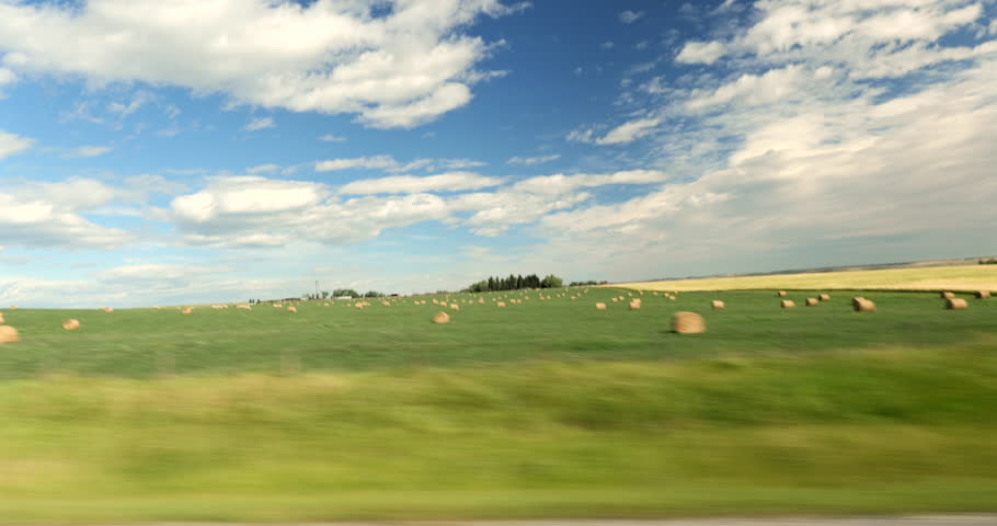Driving plate side view on a highway through open plains and farmland in Midwestern United States agricultural fields under a wide sky rural travel and American heartland concept