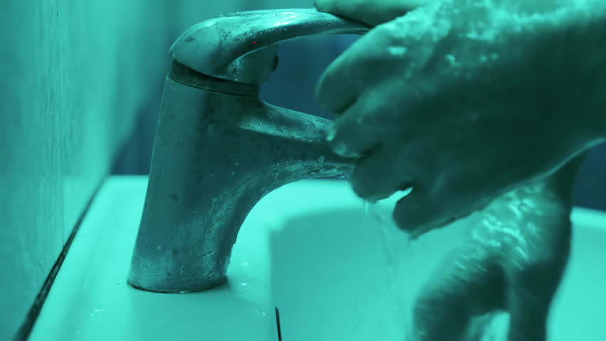 Tense Finale in Cyan-Drenched Bathroom: Thriller Climax as Man Rinses Soap and Shuts Off Faucet in Spine-Chilling Atmosphere