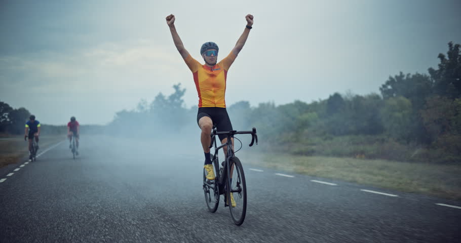 Cyclist Raises His Arms in Triumph While Crossing the Finish in Front of Competition, Celebrating a Hard-Earned Victory After an Intense Ride. His Face Lights Up with Accomplishment as He Rides