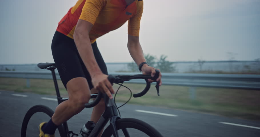 Portrait of a Cyclist Pushing Hard on a Open Road, His Legs Pumping Rhythmically as He Powers Ahead on a Professional Road Bike. His Gaze is Fixed Ahead, Reflecting His Dedication to the Training