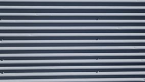 building is lined with square panels. metal sheet wall cladding with scalloped design. corrugated sheet, dark gray, riveted. horizontal stripes, shadows, corner, fence, aluminium, sheet - Powered by Shutterstock - Get 15% off with code: PIKWIZARD15