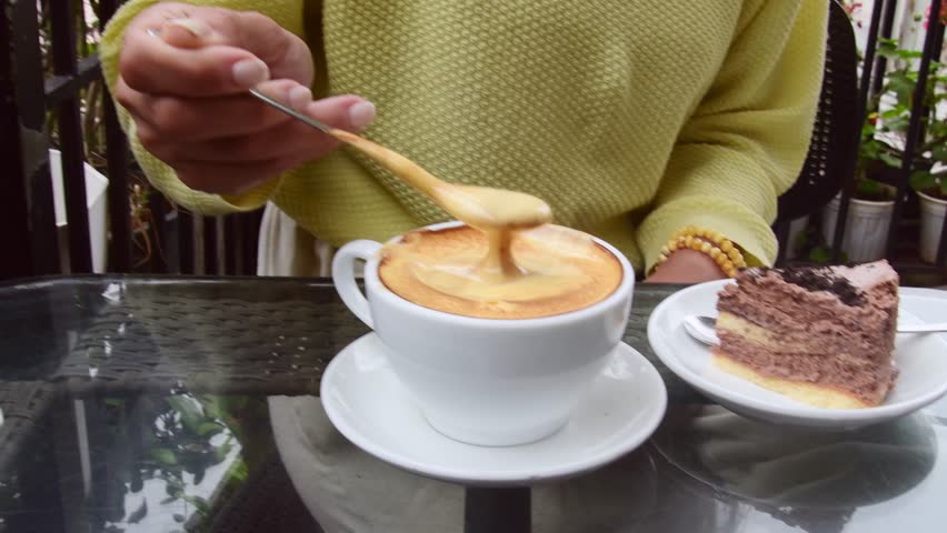 Hanoi, Vietnam - 13th february, 2024: close up woman try drink taste served egg coffee in Famous Cafe Pho Co. Egg coffee in city center. Wartime invention concept