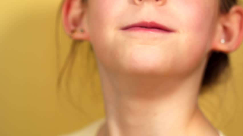 Young girl doing silly faces in front of camera. Child having fun and make a grimace with fingers in mouth while smiling and laughing.
Close up of face. Happy Child in front of yellow background.