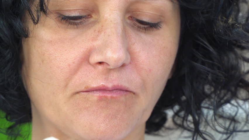 Closeup of a pretty woman licking an ice cream against while sitting on the porch swing