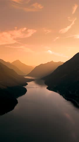 As the sun sets, its warm hues illuminate the lake Plansee winding through stunning mountains, creating a breathtaking panorama. Nature unfolds in this peaceful twilight setting. Plansee Austria