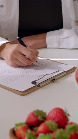 Closeup view of female nutritionist hands preparing diet plan for patient at consultation. Nutrition and diet concept. Vertical HD video.