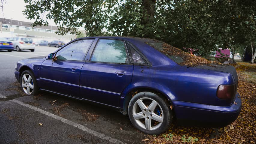 Car with dirty windows and flat tires, dry leaves fall autumn bird droppings dirt. Long standing parking car Abandoned vehicles in city after eviction or confiscation