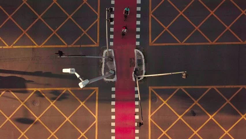 Drone footage of a São Paulo intersection at sunset, with cars and a bike lane visible, showing a vibrant urban life and city traffic.