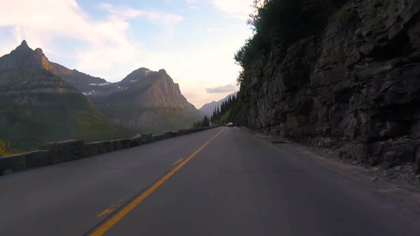 Driving on Going To The Sun Road next to the Weeping Wall during sunset at Glacier National Park, Montana, USA
