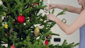 Woman decorating a christmas tree with colorful ornaments. Wearing a blue top, she has blonde hair. The tree sparkles with lights, baubles, and various festive decorations - Powered by Shutterstock - Get 15% off with code: PIKWIZARD15