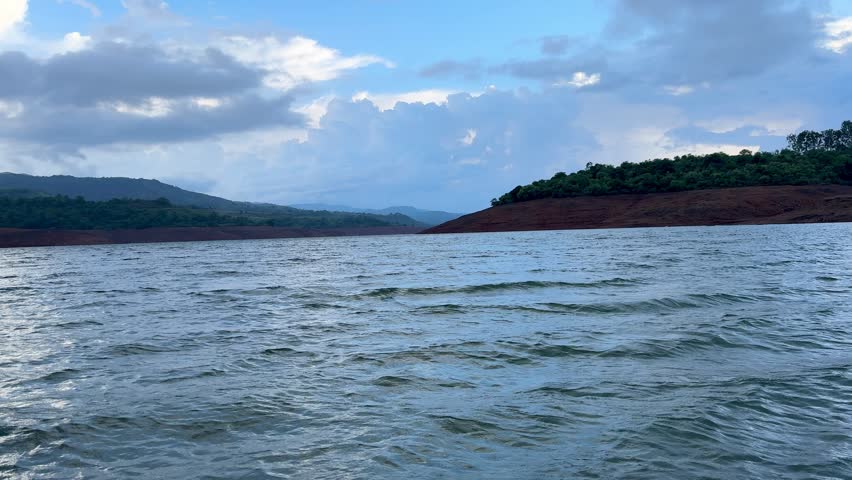 Serene evening boating on a tranquil lake, surrounded by majestic mountains, under the summer sky