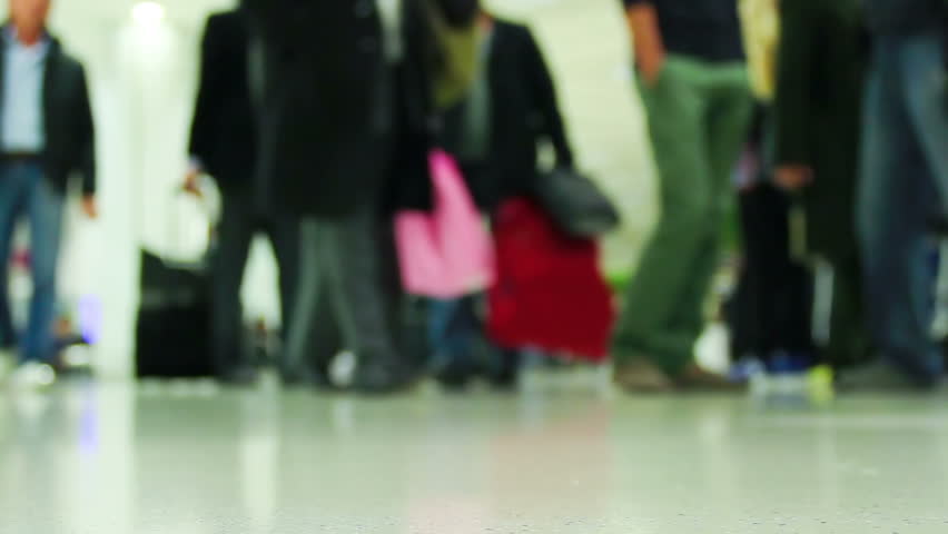 Crowd of people walking with luggage in the international airport, de-focused