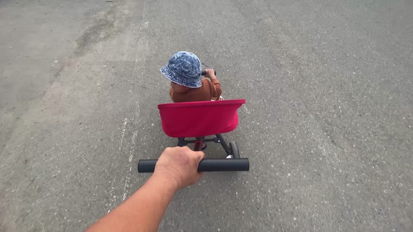 A father pushes his son on a bike, showcasing the bond between parent and child and the joy of learning.