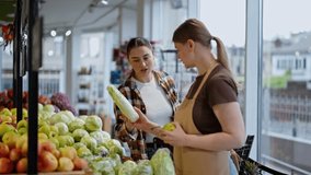 A brunette girl in a checkered shirt asks the Assistant for advice in a supermarket regarding the choice of vegetables during her shopping - Powered by Shutterstock - Get 15% off with code: PIKWIZARD15