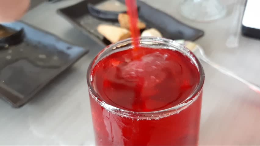 Video Footage Macro Real A Clear Transparent Collin Highball Glass Contains Delicious Fresh Red Juice Liquid From Watermelon, Wine, Beer, Soda, Cold Foggy Ice Cubes Stirred With A Stirrer. Hand Held - Powered by Shutterstock - Get 15% off with code: PIKWIZARD15