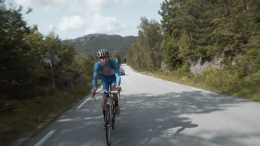 Front-Facing Follow Shot of a Road Cyclist Whizzing Down Empty Roads Amidst..