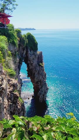 Panoramic aerial view of beautiful seascape with cliff. View from Ataturk Park to idyllic azure sea, mountains with vegetation and blue water, Antalya, Turkey. Vertical video. Taken from hand.