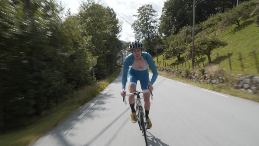 Front-Facing Follow Shot of a Road Cyclist Whizzing Down Empty Roads Amidst..
