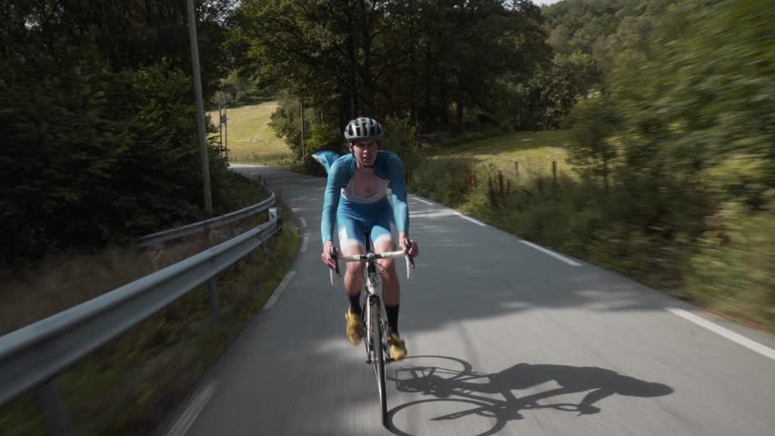 Front-Facing Follow Shot of a Road Cyclist Whizzing Down Empty Roads Amidst..