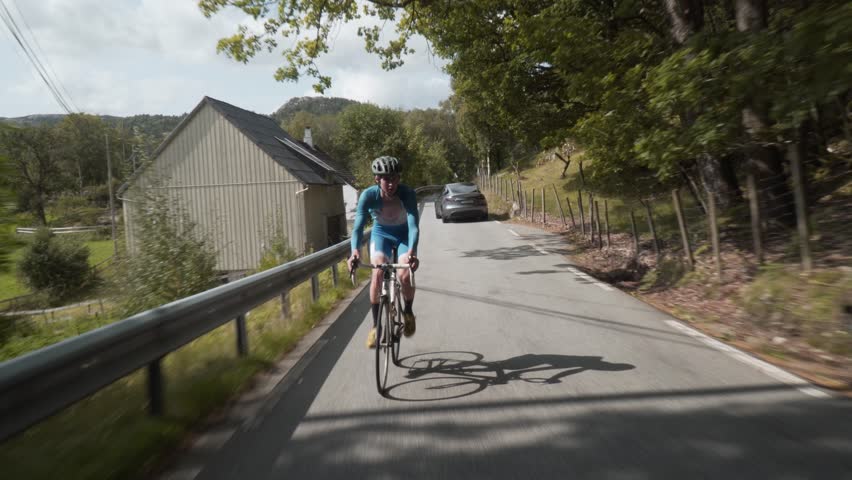 Front-Facing Follow Shot of a Road Cyclist Whizzing Down Empty Roads Amidst..