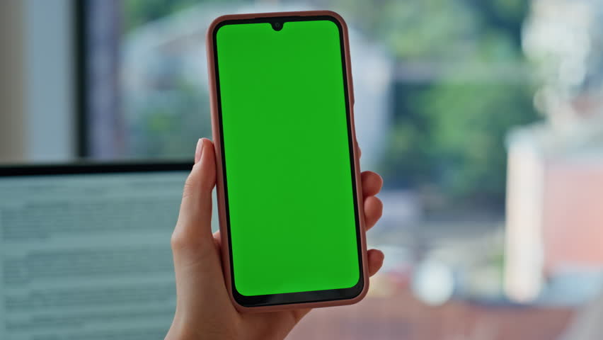 Woman fingers zooming chroma key cellphone at modern workplace closeup. Unrecognizable businesswoman watching online application on green screen smartphone. Corporate worker browse mockup mobile phone