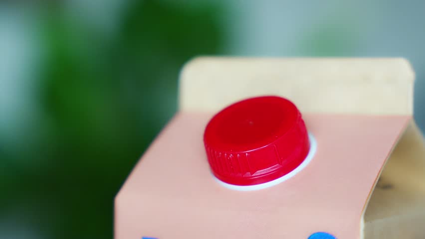 Long-life cardboard container from recycling materials with stationary plastic cap. Cap remains attached after opening, making the entire package easier to collect and recycle. High quality 4k footage