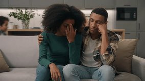 Annoyed African American ethnic exhausted young couple disturbed parents sitting sofa thinking feeling tired about noisy little boy hyperactive child misbehaving kid son playing run inside living room - Powered by Shutterstock - Get 15% off with code: PIKWIZARD15