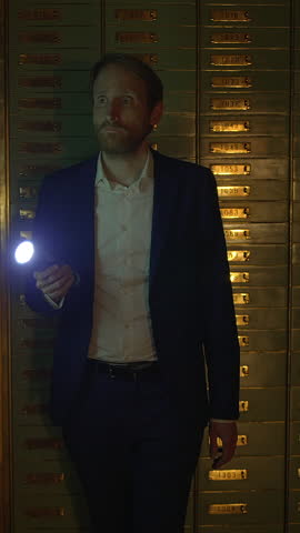A man holding a flashlight stands confidently in front of a striking golden wall