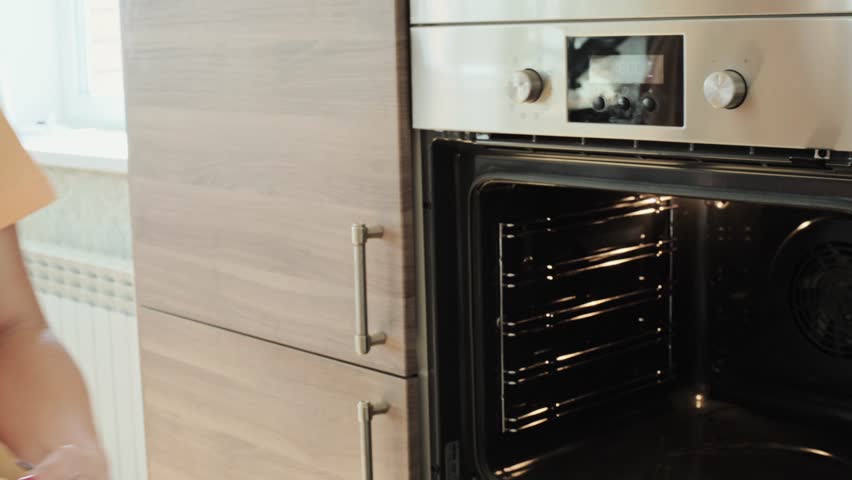 a girl cooks pizza with vegetables at home, puts a baking sheet with pizza in the oven, the concept of healthy homemade food. High quality 4k footage