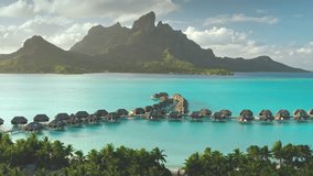 Aerial view overwater bungalows forming line towards mount Otemanu on tropical exotic Bora Bora island, with its turquoise lagoon and lush vegetation. Luxury travel vacation resort in coral reef ocean - Powered by Shutterstock - Get 15% off with code: PIKWIZARD15