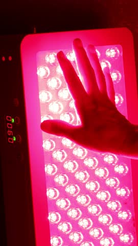 Closeup of hand touching Red Light Therapy Panel LEDs