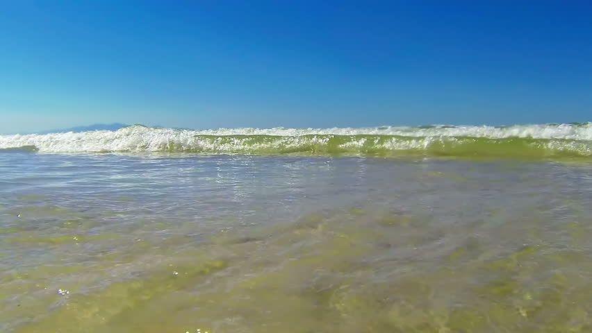 Small ocean wave hitting camera