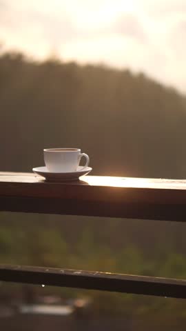 beautiful vertical video portrait a cup of coffee with milk stirred in a white glass on the table in the afternoon