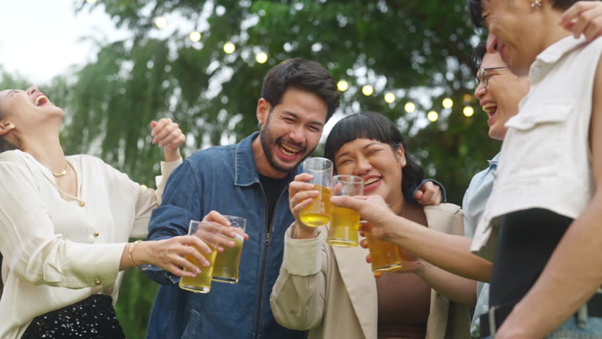 Group of Happy Asian millennial generation people friends enjoy and fun toasting beer glasses celebration reunion meeting at outdoor dinner party in the garden at restaurant on holiday vacation.