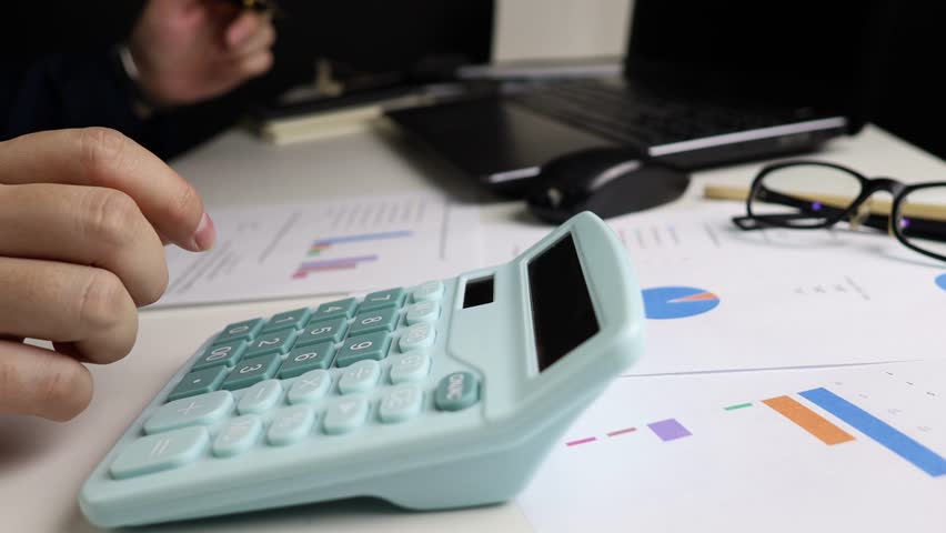 Close up of Male Hand Using a Calculator to Compute Family Income for Household Accounting, Focusing on Financial Management and Budgeting