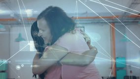 Animation of network and data processing over happy diverse female colleagues embracing at office. Business, connection, teamwork, digital interface and communication, digitally generated video. - Powered by Shutterstock - Get 15% off with code: PIKWIZARD15