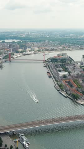 Vertical video. Rotterdam, Netherlands. Erasmus Bridge. Noordereiland Island. View of the city center. River Nieuwe Maas. Summer day, Rainy clouds, Aerial View