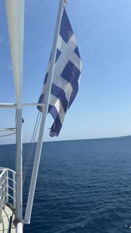 Greek national flag waving and the water wake done by a speeding boat