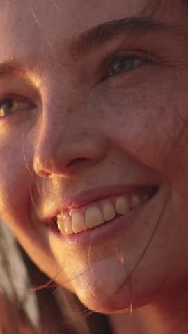 A close-up of a smiling woman with natural freckles, illuminated by the soft morning sunlight. Ideal for promoting beauty, natural skincare, outdoor lifestyle, and positive energy concepts. Vertical