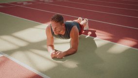 Sportsman performs plank exercise on running track in gym. Motivated man in tank top and shorts improves core strength and endurance during workout - Powered by Shutterstock - Get 15% off with code: PIKWIZARD15