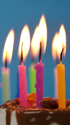 Lighted candles in a birthday cake rotation on a blue background. Candles in birthday cheesecake for home party.