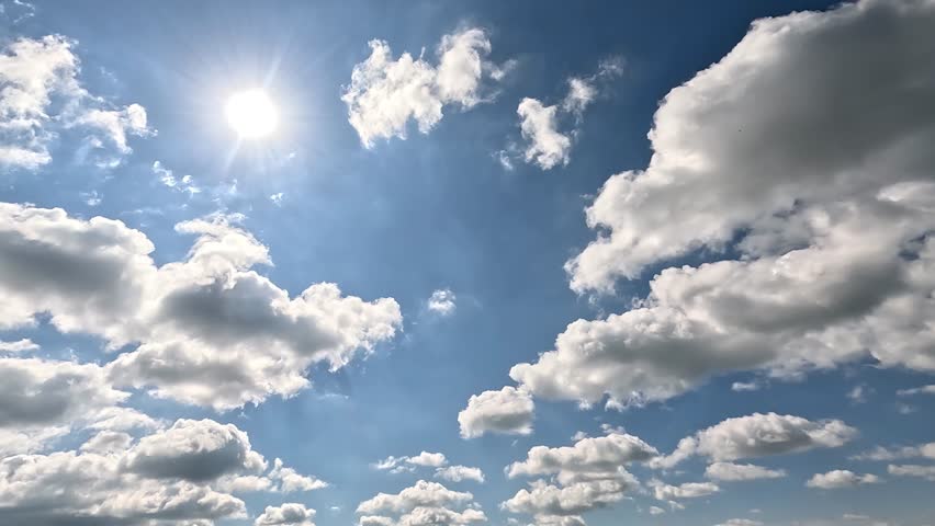 Beautiful Endless Clouds in the Daylight Skies. 4K video (Ultra High Definition) of cloudscape and bright sun. Sky and clouds Timelapse. Ssun shines through the clouds on the blue sky background.