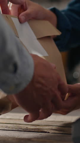 The courier picks up the package with the food order for delivery to the customer. The operator behind the counter gives the order to the courier for food delivery. Paper packaging food bag