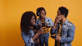 Enthusiastic father playing online video games with baby boy using controller, both parents enjoying leisure time with their small kid. African american happy family play with joystick. Camera B. - Powered by Shutterstock - Get 15% off with code: PIKWIZARD15