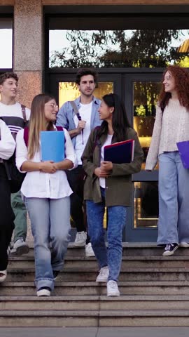 Vertical. Large group international smiling young students walking down stairs leaving the university building talking cheerful. Community of generation z happy people friends relationships on campus