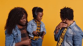 Enthusiastic father playing online video games with baby boy using controller, both parents enjoying leisure time with their small kid. African american happy family play with joystick. Camera A. - Powered by Shutterstock - Get 15% off with code: PIKWIZARD15
