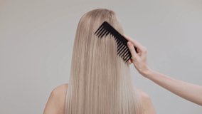 A blonde girl is combing her chic long straight hair in the studio on a light background. - Powered by Shutterstock - Get 15% off with code: PIKWIZARD15