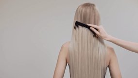 A blonde girl is combing her chic long straight hair in the studio on a light background. - Powered by Shutterstock - Get 15% off with code: PIKWIZARD15
